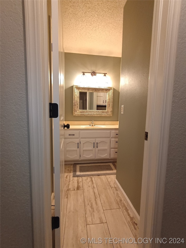 bathroom with vanity, wood-type flooring, and a textured ceiling