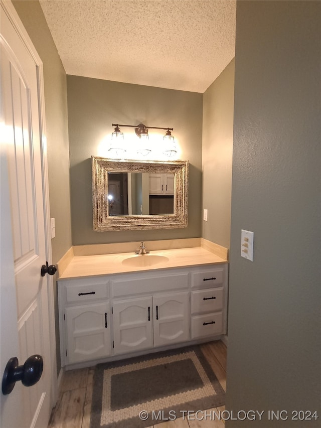 bathroom with vanity, a textured ceiling, and hardwood / wood-style flooring