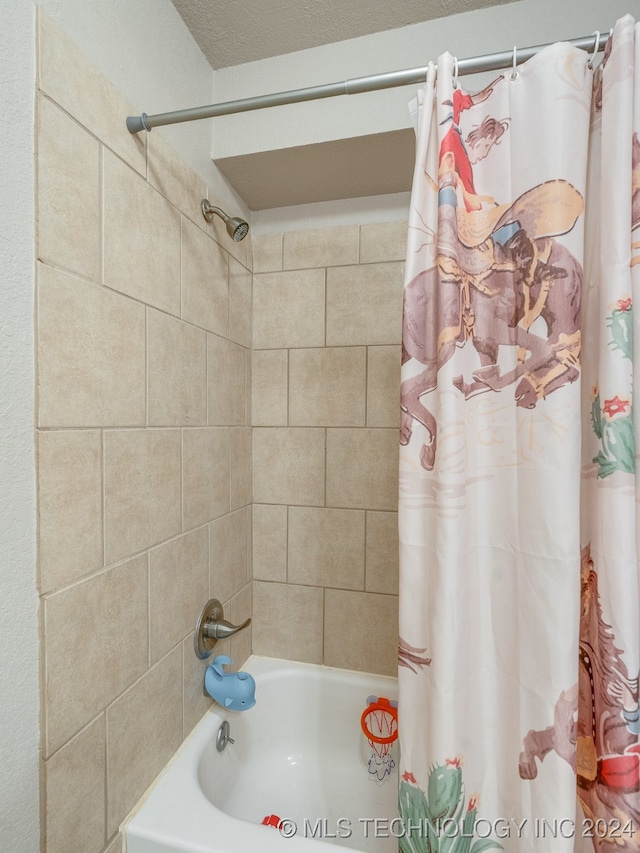 bathroom with shower / bath combination with curtain and a textured ceiling