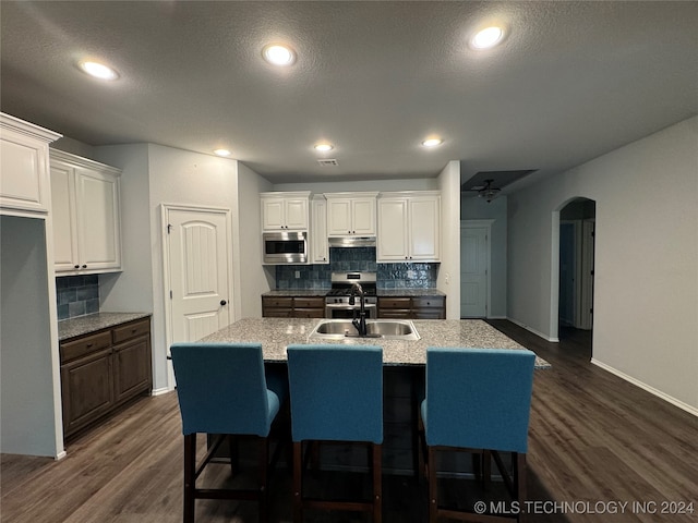 kitchen featuring stainless steel appliances, white cabinetry, a kitchen island with sink, and dark hardwood / wood-style floors