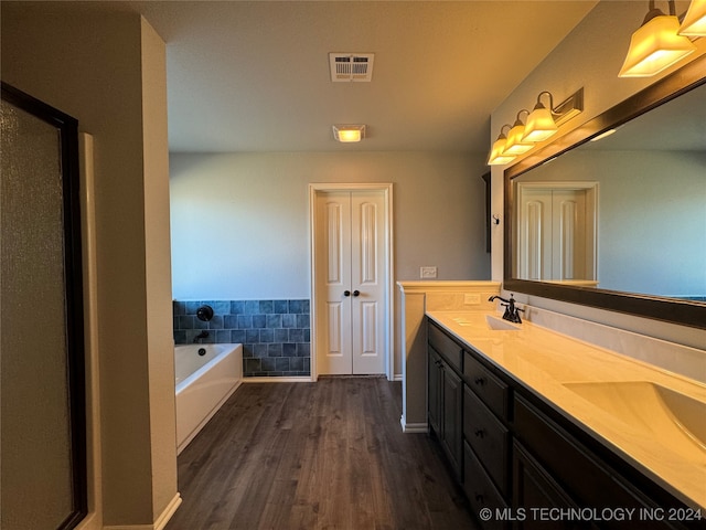 bathroom featuring a bathtub, vanity, wood-type flooring, and tile walls