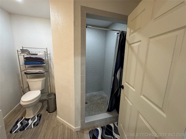 bathroom featuring a shower with shower curtain, hardwood / wood-style flooring, and toilet