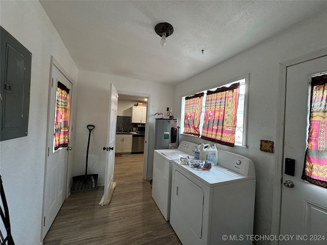 laundry area featuring hardwood / wood-style floors, electric panel, washer and dryer, a textured ceiling, and water heater