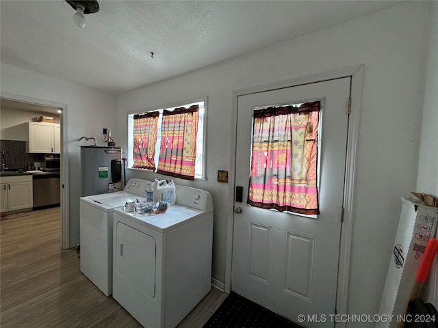 laundry room with washing machine and clothes dryer, water heater, hardwood / wood-style floors, and a textured ceiling