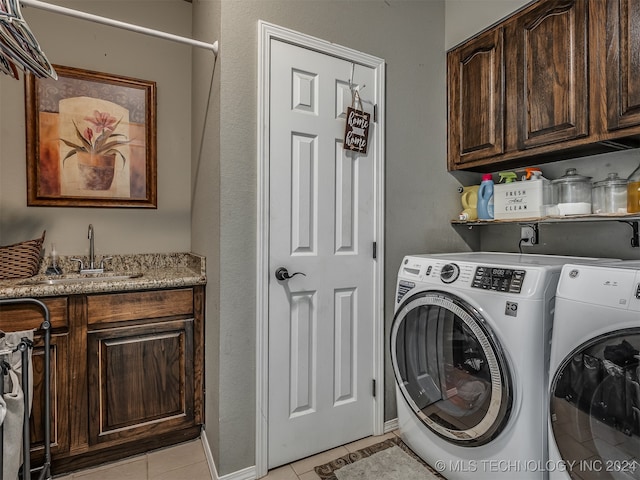 clothes washing area with light tile patterned flooring, cabinets, sink, and washing machine and dryer