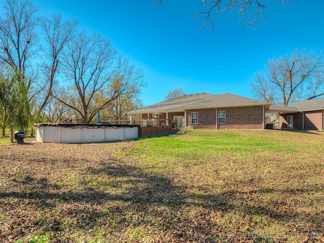 rear view of property with a yard and a covered pool