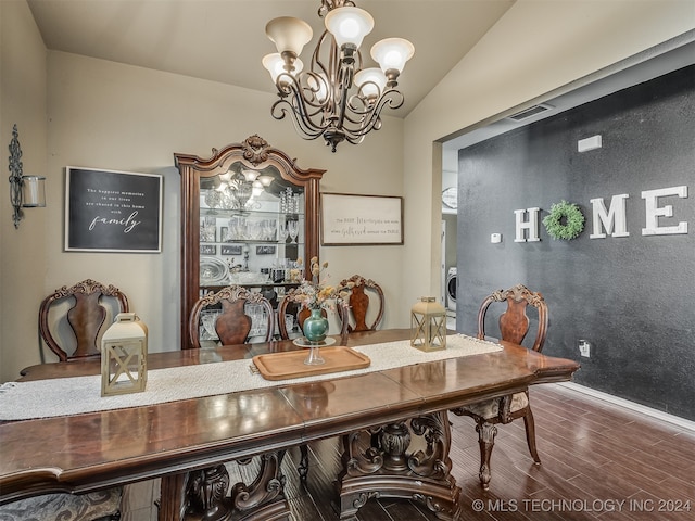 dining room with lofted ceiling, washer / dryer, wood-type flooring, and a chandelier