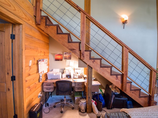 carpeted office space with a high ceiling and wooden walls