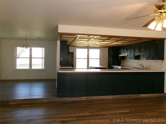 kitchen featuring ceiling fan with notable chandelier, a healthy amount of sunlight, kitchen peninsula, and dark wood-type flooring