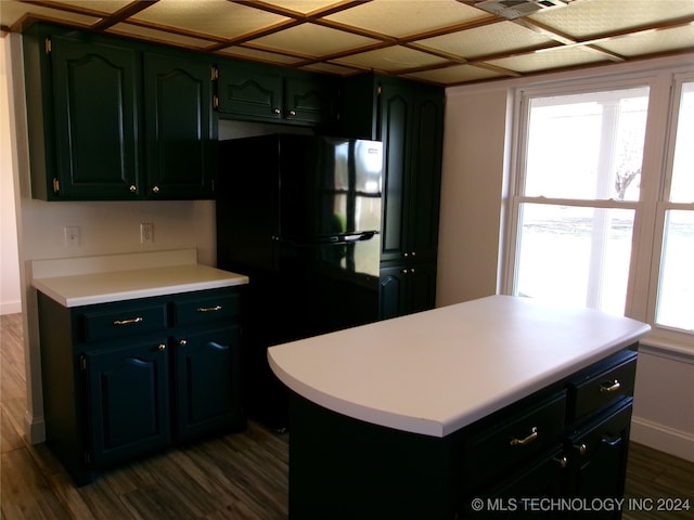 kitchen with a center island, black fridge, green cabinetry, and dark wood-type flooring