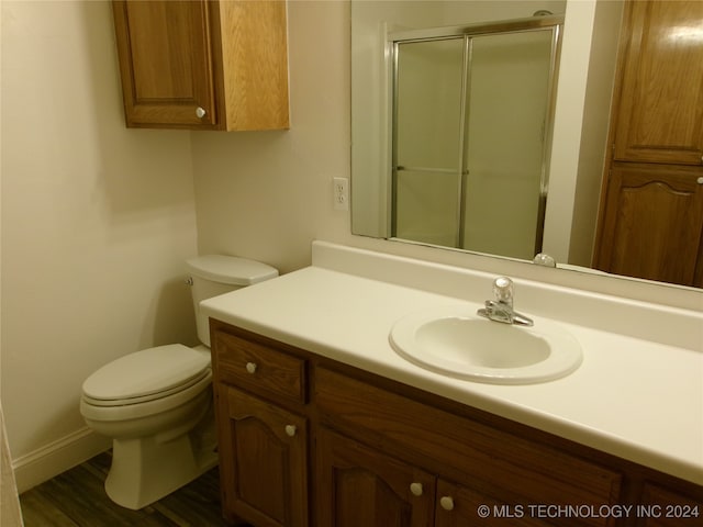 bathroom featuring wood-type flooring, vanity, toilet, and a shower with shower door