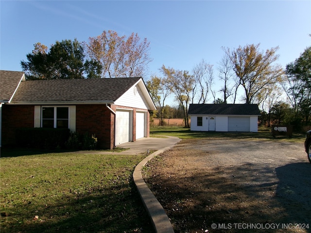 view of side of property with a yard, an outbuilding, and a garage