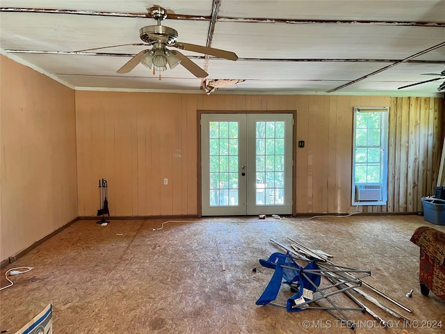 unfurnished room with a wealth of natural light, french doors, ceiling fan, and wooden walls