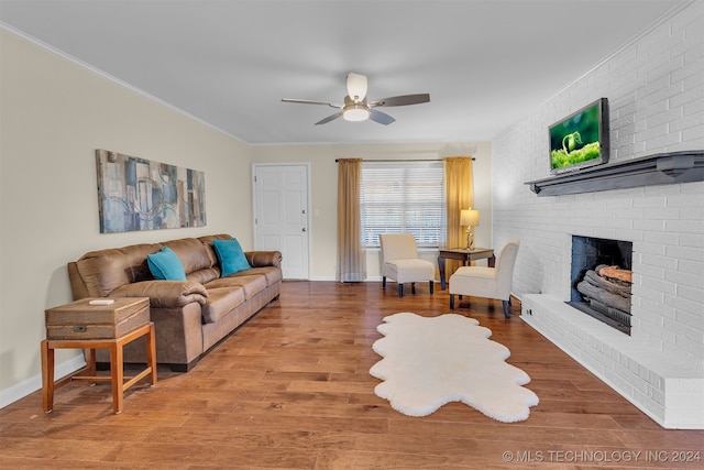 living room featuring hardwood / wood-style flooring, a brick fireplace, ceiling fan, and ornamental molding