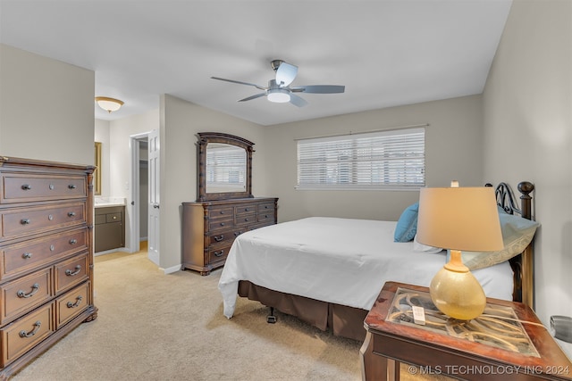 bedroom featuring ceiling fan, light colored carpet, and ensuite bath