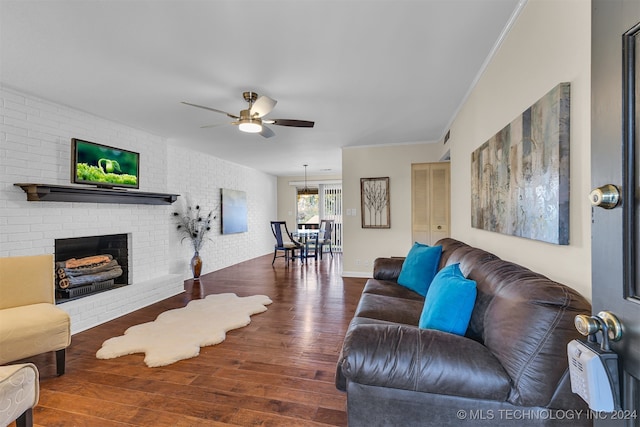 living room featuring ceiling fan, dark hardwood / wood-style flooring, ornamental molding, and a brick fireplace