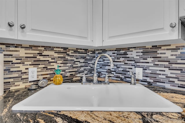 details featuring dark stone countertops, white cabinetry, and sink