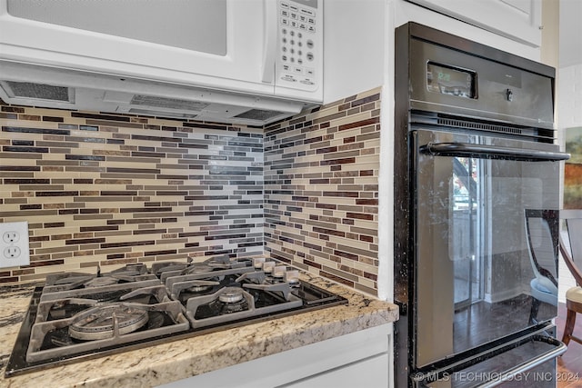 kitchen featuring white cabinets, black oven, stainless steel gas cooktop, and tasteful backsplash