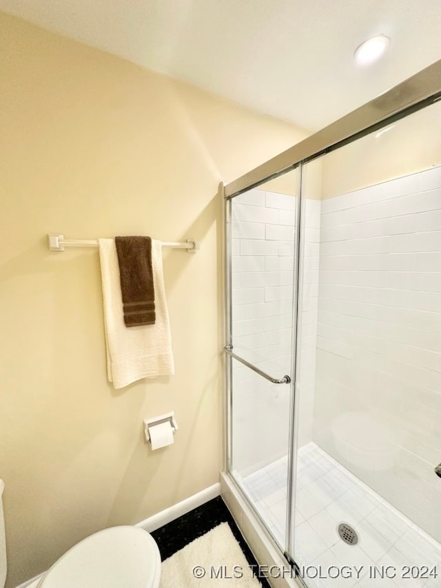 bathroom with toilet and a shower with shower door