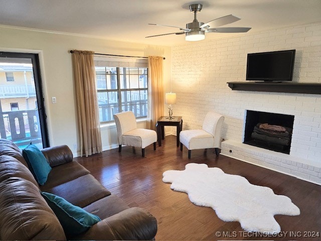 living room featuring a brick fireplace, ornamental molding, brick wall, ceiling fan, and dark hardwood / wood-style floors