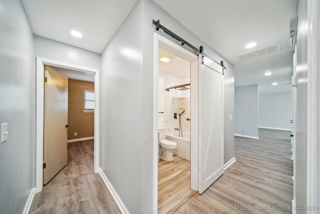 hall with a barn door and light hardwood / wood-style flooring