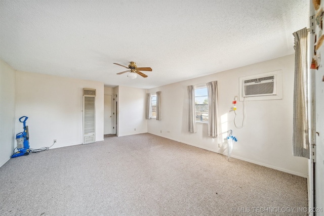 carpeted spare room featuring ceiling fan, an AC wall unit, and a textured ceiling