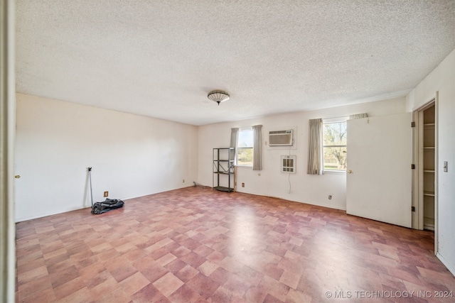 empty room with a wall mounted air conditioner and a textured ceiling