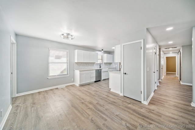 kitchen with dishwasher, a barn door, light hardwood / wood-style floors, decorative backsplash, and white cabinets