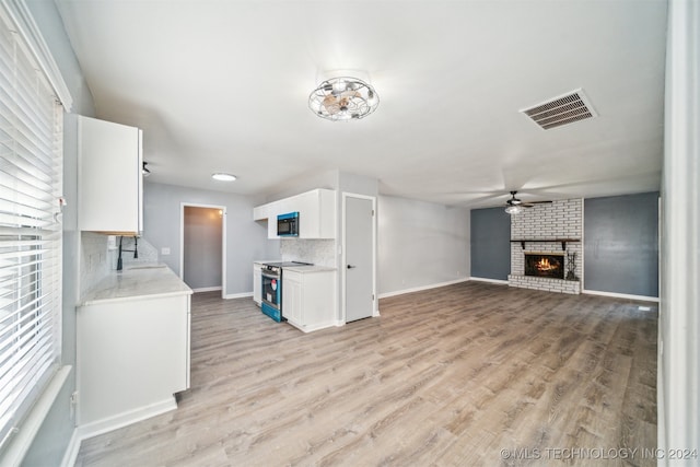 unfurnished living room with light hardwood / wood-style floors, a brick fireplace, ceiling fan, and sink