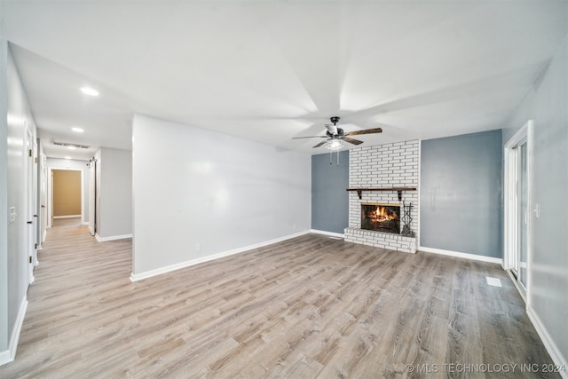 unfurnished living room featuring a brick fireplace, ceiling fan, and light wood-type flooring