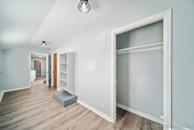 unfurnished bedroom featuring a closet, light hardwood / wood-style flooring, and lofted ceiling