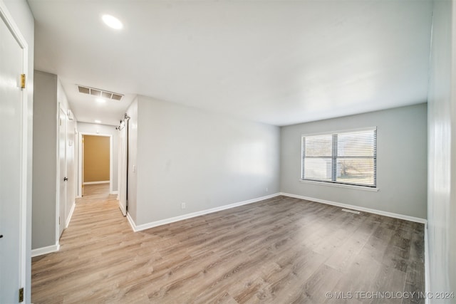 empty room featuring light hardwood / wood-style floors and a barn door