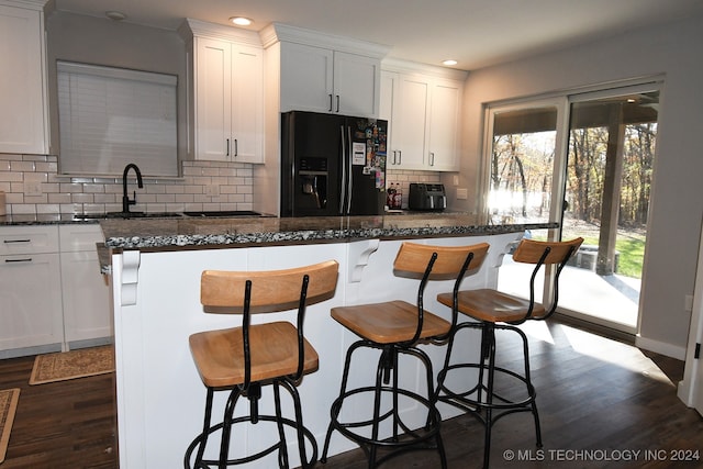 kitchen featuring black fridge, sink, dark hardwood / wood-style flooring, and white cabinetry