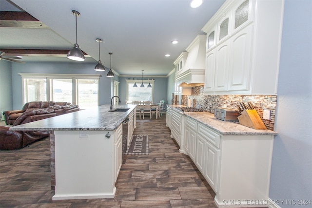 kitchen featuring backsplash, white cabinetry, crown molding, and decorative light fixtures