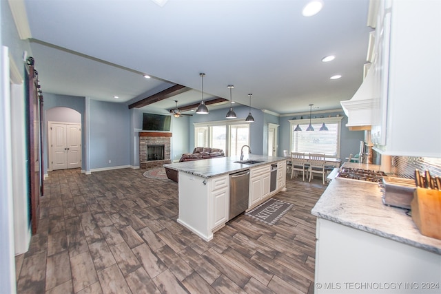 kitchen featuring a center island with sink, stainless steel dishwasher, dark hardwood / wood-style floors, decorative light fixtures, and white cabinetry