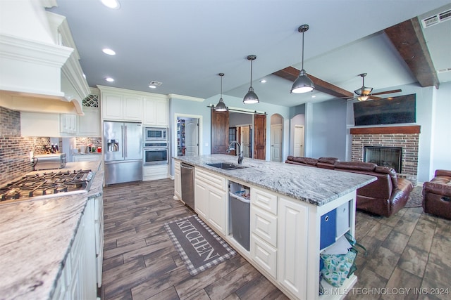 kitchen with a center island, sink, stainless steel appliances, backsplash, and white cabinets