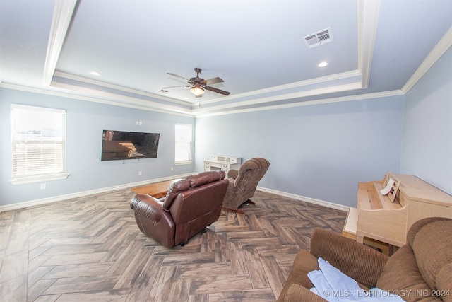 cinema room with a raised ceiling, dark parquet flooring, ceiling fan, and ornamental molding