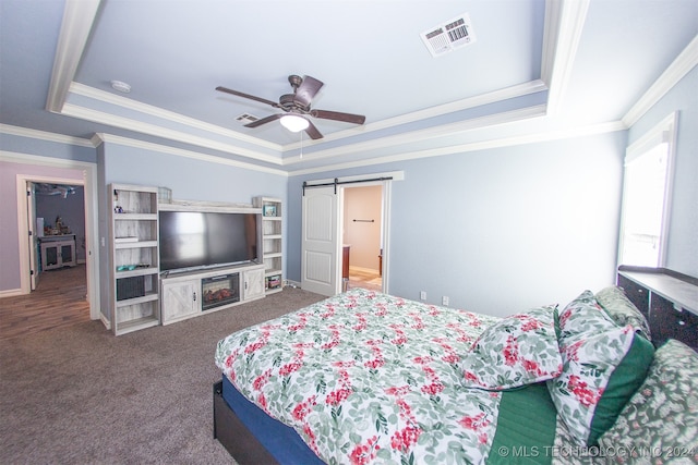 bedroom with carpet, a raised ceiling, ceiling fan, a barn door, and ornamental molding