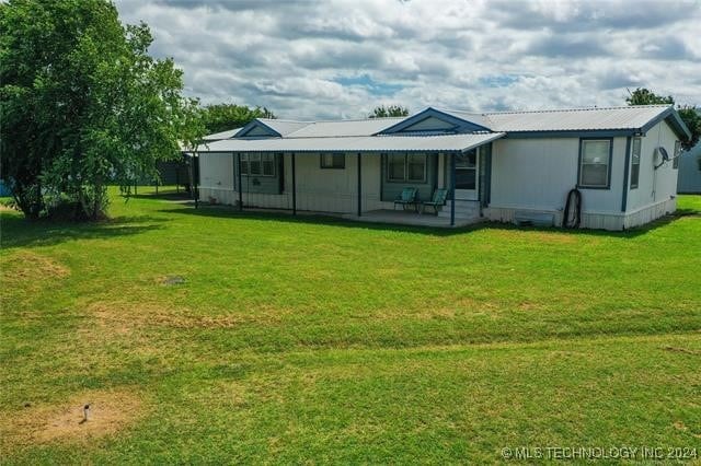 back of property featuring covered porch and a yard