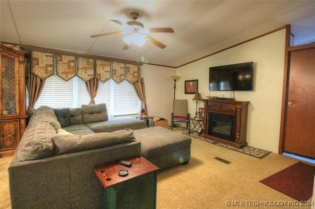 carpeted living room with ceiling fan and vaulted ceiling