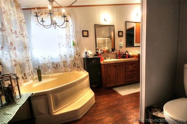 bathroom featuring a tub, an inviting chandelier, toilet, vanity, and hardwood / wood-style flooring