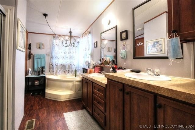 bathroom with wood-type flooring, vanity, a tub, and a notable chandelier