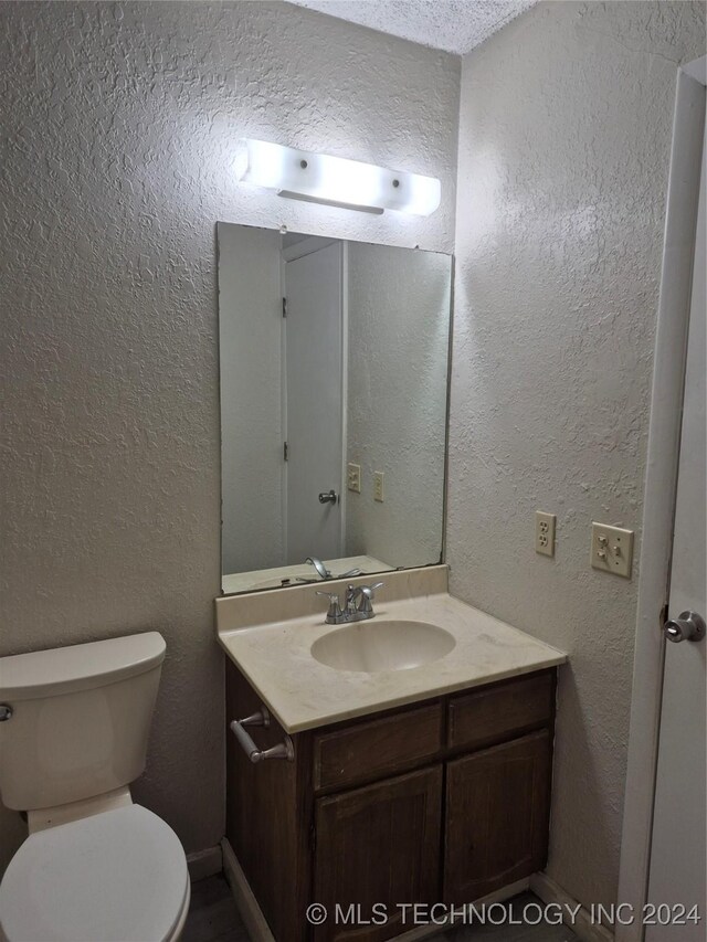 bathroom featuring vanity, toilet, and a textured ceiling