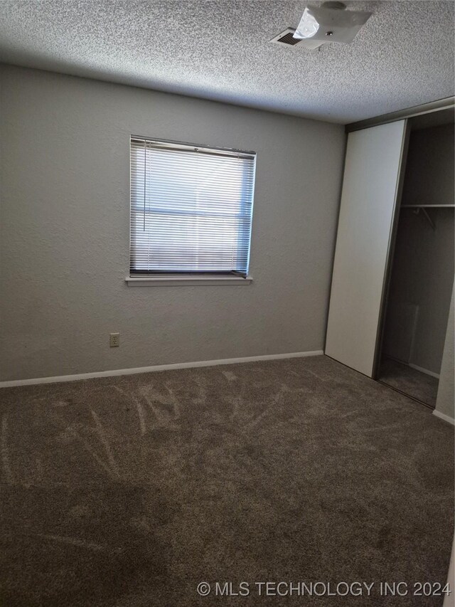 unfurnished bedroom featuring a closet, carpet floors, and a textured ceiling