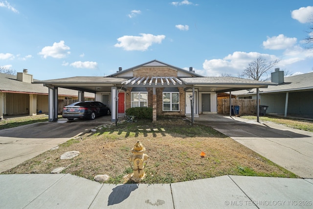 view of front of home with a carport, brick siding, concrete driveway, and fence