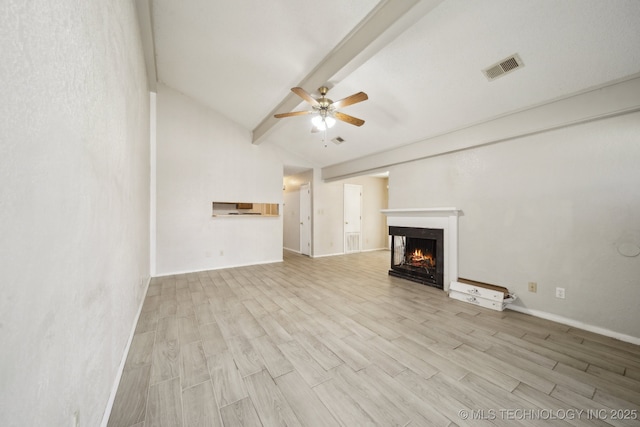 unfurnished living room with lofted ceiling with beams, light wood-style floors, a lit fireplace, and visible vents