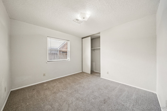 unfurnished bedroom with baseboards, visible vents, carpet, a textured ceiling, and a closet