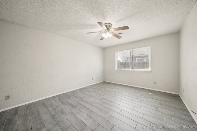 spare room featuring a ceiling fan, visible vents, a textured wall, and wood finished floors