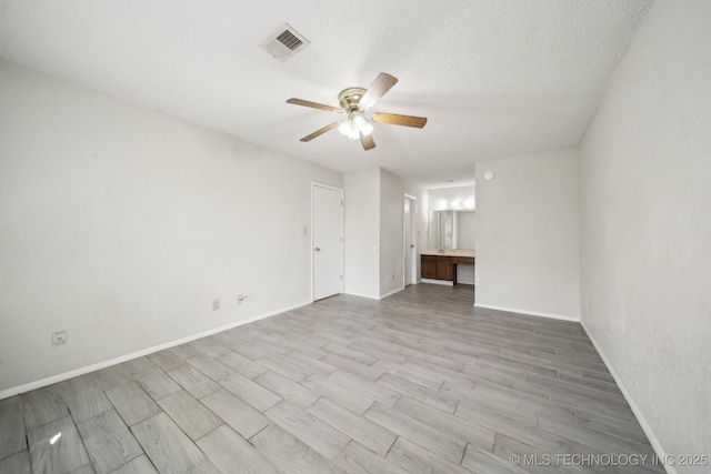 spare room featuring baseboards, visible vents, a textured ceiling, and wood finished floors