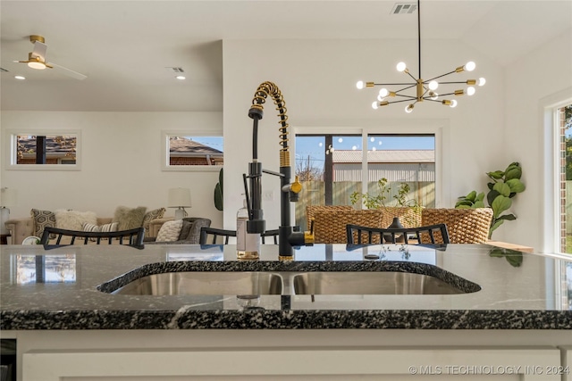 kitchen with plenty of natural light, decorative light fixtures, sink, and dark stone counters